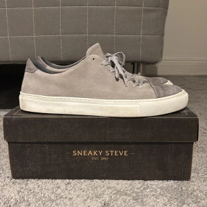 Sneaky Steve Lescape Grå Sneakers  - Säljer ett par snygga sneakers från Sneaky Steve i grå mocka med en läder toe cap. Skorna är i väldigt bra skick 9/10 då de knappt använts. Nypris 1200 kr, men de är svåra att få tag på då de inte längre tillverkas, vilket gör de exklusiva! 