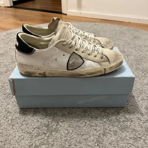 Vita sneakers från Philippe Model - Säljer ett par vita sneakers från Philippe Model i bra skick. Dustbag följer med, box är inte original men kan fås med vid lite dyrare. De är lite slitna på sulan men fortfarande snygga och bekväma. Perfekta för vardagsbruk! Strlk 42 passar ej 43