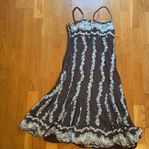 Blommig klänning från Twist & Tango - Säljer en superfin blommig klänning från Twist & Tango i storlek M. Klänningen har smala axelband och ett vackert blommönster i blått och vitt på en mörk bas. 🌸 Defekt i i vänstra bandet där det har satts en säkerhetsnål istället. 