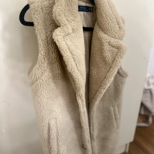 Beige pälsväst från Polo Ralph Lauren - Aldrig använd, storlek xxs men passar även dig som har xs s o även m. Den är väldigt lång, nästan till vaderna 