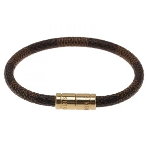 Louis Vuitton Brunt armband med gulddetaljer - Snyggt och stilrent armband i brunt med guldfärgad låsdetalj. Perfekt för både vardag och fest, och ger en elegant touch till vilken outfit som helst. Armbandet är i mycket bra skick och passar de flesta handleder.