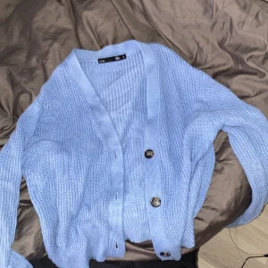 Ljusblå stickad kofta från 157 - Superfin ljusblå stickad kofta från 157 i storlek S. Den har en avslappnad passform med stora knappar framtill. Perfekt för lager-på-lager under hösten eller våren. Koftan är mjuk och bekväm, idealisk för både vardag och mysiga hemmakvällar. 💙