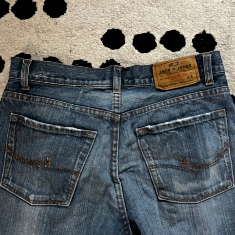 Säljer ett par klassiska blå jeans från Jack & Jones. De är i bra skick med en liten reva på ena benet för en cool look. Perfekta för vardagsbruk och passar till det mesta. De är mid rise och är superbekväma att ha på sig. Jag är 169 cm lång. Köparen står för frakt, skickar spårtbart PostNord paket.. Jeans & Byxor.