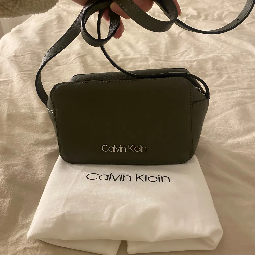 Snygg grön axelväska från Calvin Klein i mycket bra skick. Väskan har en stilren design med dragkedja och justerbar axelrem. Perfekt för både vardag och fest! Kommer med originalpåse.. Väskor.