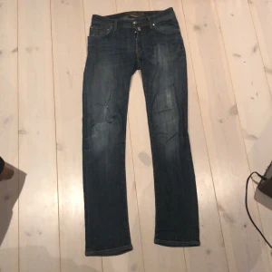 Blå jeans från Jacob Cohen - Säljer ett par snygga blå jeans från Jacob Cohen i bra skick. De har en klassisk femficksdesign och är tillverkade av exklusiva material med italienskt hantverk. Perfekta för både vardag och fest!Det har varit ett hål som jag senare har sytt igen nu ser det ut som en snygg slitning pris kan diskuteras ÄKTA 