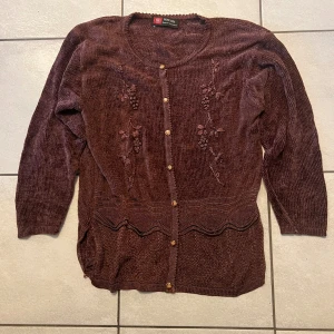 Brun Kashmir tröja  - Mysig brun kofta i stickat material med fina detaljer och träknappar. Perfekt för höst och vinter. Koftan har långa ärmar och ett dekorativt mönster framtill. Passar bra till både vardag och lite finare tillfällen.