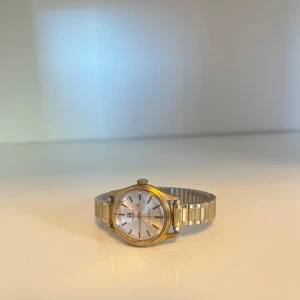 Tissot Actalis damklocka i guldpläterat stål - Tissot Actalis damklocka i guldpläterat stål. Klockan har ett vitt urtavla med guldpläterade visare och index. Klockan är utrustad med ett automatiskt urverk. Klockan är i gott skick med normala användningsspor.