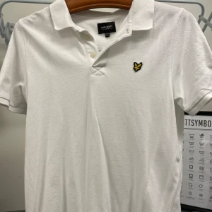 Vit pikétröja från Lyle & Scott - Säljer en klassisk vit pikétröja från Lyle & Scott i storlek 14/15 y(passar även lite mindre än S). Tröjan har en broderad logga på bröstet och är kortärmad med en stilren krage. Perfekt för både vardag och fest! Bara att kontakta mig vid frågor