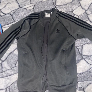 Grå adidas sst - Grå adidas sst zip up i riktigt bra skick. Använd ett par gånger bara. Storlek S