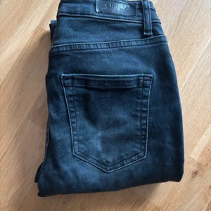 Svarta jeans från ONLY - Säljer ett par svarta jeans från ONLY i storlek S. De är i bra skick och har en klassisk femficksdesign med knapp och dragkedja framtill. Perfekta för både vardag och fest! 🖤. Långa för mig som är 178 cm lång. Storlek S/32