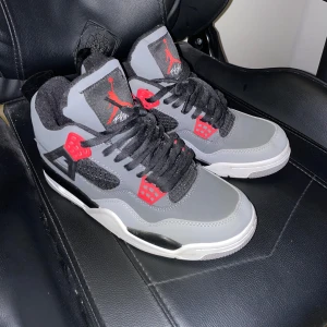 Nike Air Jordans i grått och rött - Säljer ett par snygga Nike Air Jordans i grått med röda detaljer. Skorna har svart snörning och en vit sula. Perfekta för både vardag och fest! De är i mycket bra skick och redo för nya äventyr.