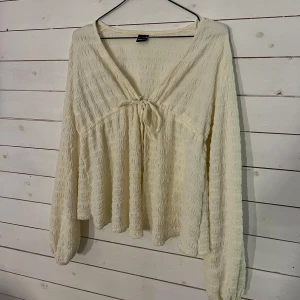 Beige blus med knytning - säljer en superfin beige blus med lång ärm och knytning framtill. den har en luftig och bekväm passform, perfekt för både vardag och festligheter. använd 1-2 gånger därav säljer jag den 🥰