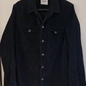 Svart manchesterjacka från Jack & Jones - Säljer en snygg svart manchesterskjorta från Jack & Jones i storlek XS. Knappar framtill samt två bröstfickor med knappar. Perfekt för höst och vår! 🖤