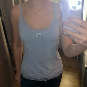 Ljusblå linne med spetsdetaljer - Säljer ett supersött ljusblått linne med spets och en liten rosett framtill. Perfekt för sommaren eller att sova i! Använd 1-2 gånger, så är i mycket bra skick! 💞