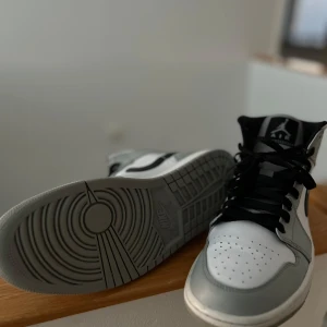 Nike Air Jordans i grått och vitt - Säljer ett par Nike Air Jordans i grått och vitt. Skorna har en klassisk design med svart swoosh och snörning. Perfekta för både vardag och fest. Sulan är i mycket bra skick och ger bra grepp. Passar perfekt för dig som vill ha stil och komfort i ett.