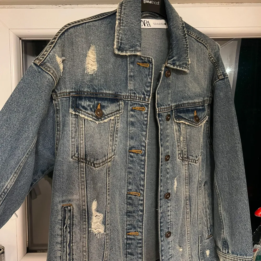 Säljer en jeansjacka från Zara som är knappast använd. Den har en klassisk blå denimfärg med slitna detaljer som ger en vintagekänsla. Den är i storlek XS men är oversized. . Jackor.