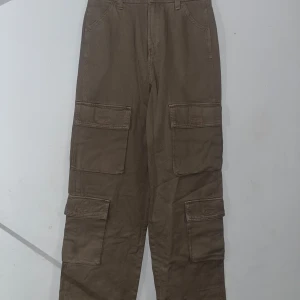 Bruna cargobyxor - Säljer ett par bruna cargobyxor i bra skick. De har flera praktiska fickor och en loose passform, perfekt för en avslappnad stil. Byxorna är tillverkade i ett slitstarkt material och passar bra till höst och vår.