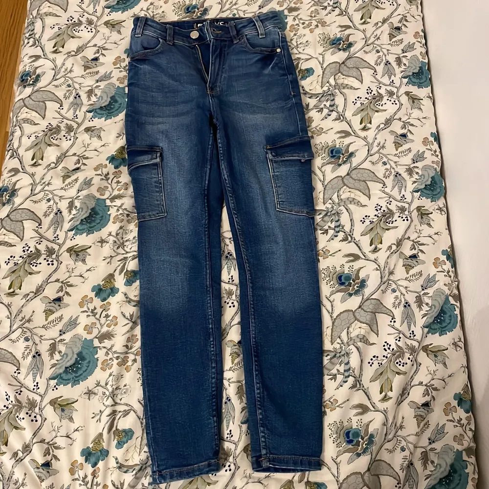 Säljer ett par snygga blå skinny cargo jeans från FB Sister i storlek XS. De har praktiska cargofickor på sidorna och en tight passform som ger en modern look. Perfekta för både vardag och fest! 🦋. Jeans & Byxor.