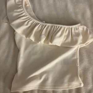 Vit oneshoulder topp med volang från hm - Toppen köptes för 150, och den har använts ca 2 gånger🤍