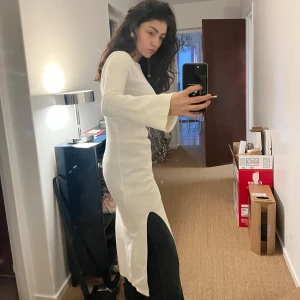 Vit ribbad klänning - Säljer en superfin vit ribbad klänning i mycket bra skick. Den är långärmad och har en slits på sidan som ger en snygg detalj samt öppen rygg. Perfekt för både höst och vår, och kan stylas upp eller ner beroende på tillfälle. Klänningen är tight och framhäver figuren på ett smickrande sätt.