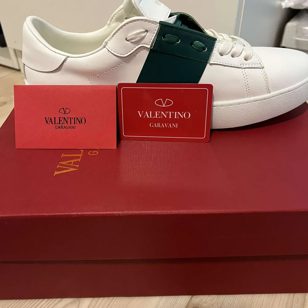 Säljer ett par snygga Valentino Garavani sneakers i vitt och grönt. Skorna är i nytt skick och kommer med originalförpackning och dustbag. Perfekta för både vardag och fest med sin stilrena design och högkvalitativa material.. Skor.