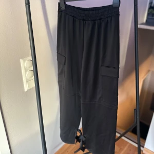 Svarta cargopants HM - Svarta cargopants i mycket bra skick. De har en elastisk midja och en snygg detalj nere vid anklarna.