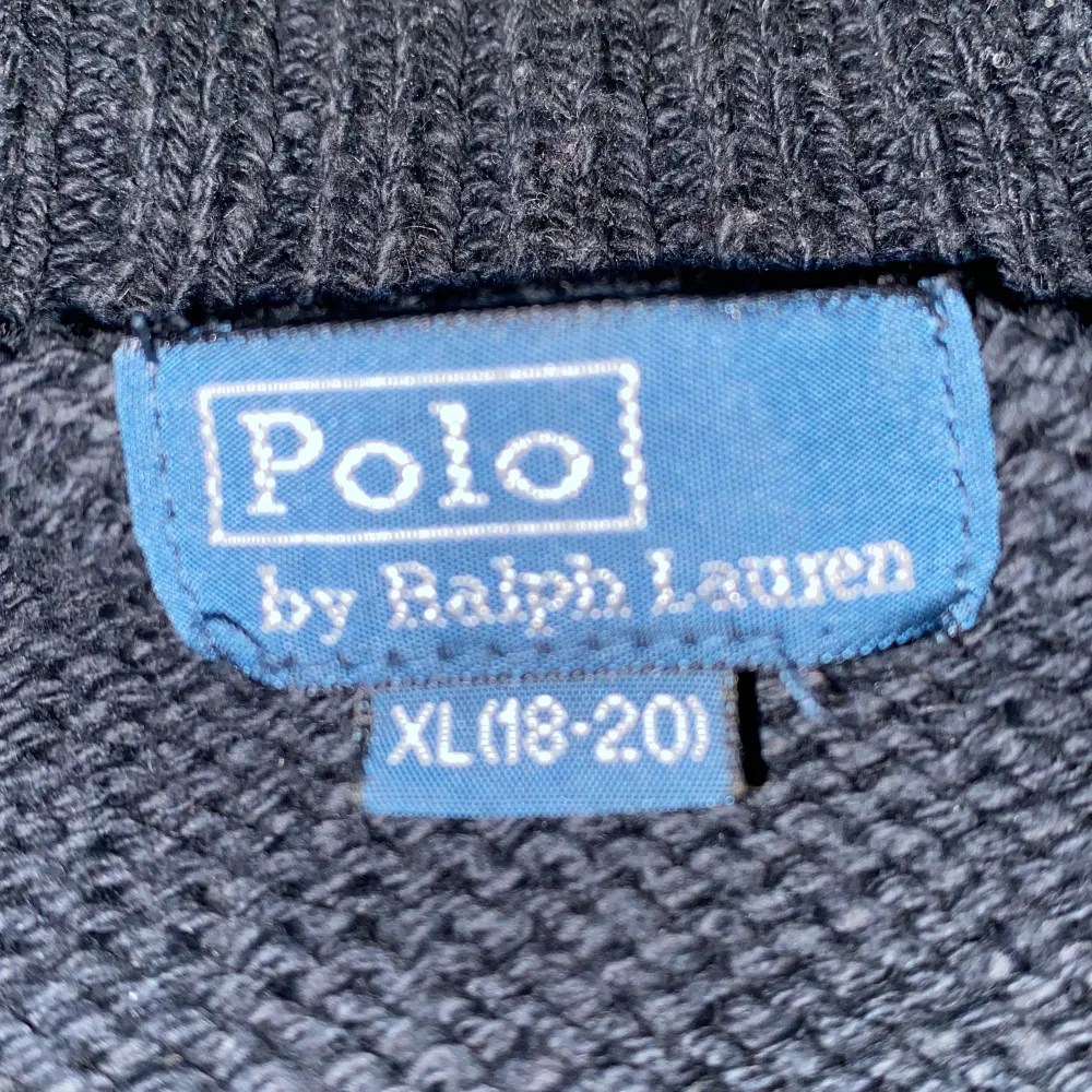 Säljer en snygg svart stickad tröja från Polo Ralph Lauren med en cool amerikansk flagga på framsidan och RL67 broderat. Tröjan har en dragkedja vid halsen och är perfekt för höst och vinter. Den är i mycket bra skick och supermysig att ha på sig!. Tröjor & Koftor.