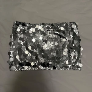 Glittrig silver kort minikjol med paljetter och shorts low waist - Säljer en glittrig kjol i silver med paljetter och undershorts. Perfekt för fest eller nyår! Den är stretchig och sitter bekvämt. Kort modell med låg midja!