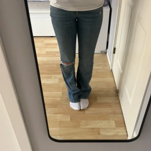 Blå jeans med slitningar - Säljer ett par snygga blå jeans från Gina. Använda ett fåtal gånger men säljer för att midjan är för liten för mig. Jeansen är bootcut med slitning på knäet och med en mid waist. 💕
