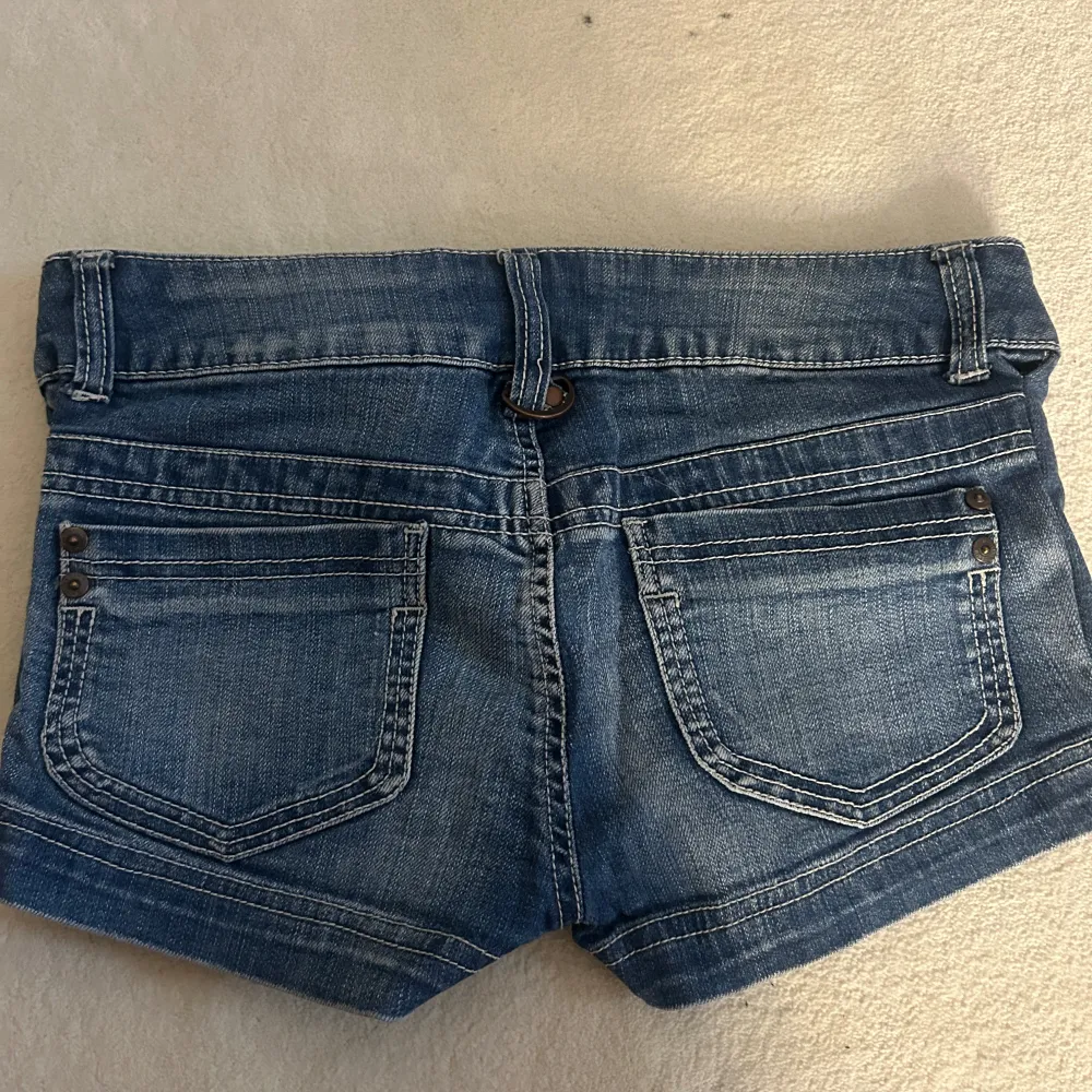 Säljer ett par snygga blå jeansshorts från ONLY i bra skick. De är lågmidjade med en klassisk femficksdesign och har en knapp och dragkedja framtill. Perfekta för sommardagar eller festivaler! 🕶️. Shorts.