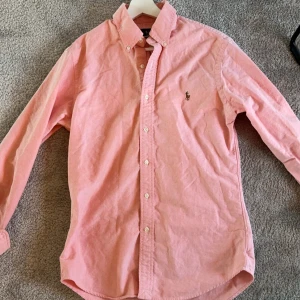 Ralph Laurent skjorta  - Säljer en snygg rosa skjorta från Ralph Lauren i storlek M. Skjortan är i slim fit och har långa ärmar med knappar. Den är tillverkad i bomull och har en broderad logga på bröstet. Perfekt för både vardag och fest! Nypris ca 1700, mitt pris 649!🤩 billigare vid snabb affär!