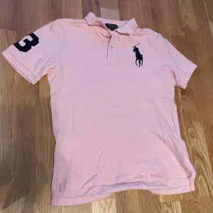 Ralph Lauren Piké  - Tja!                                                                   Säljer en snygg rosa 🩷pikétröja 👕från Ralph Lauren 🏇🏻i storlek xs som passar 158-164. Tröjan har används sparsamt. Perfekt för en avslappnad men stilren ⚜️            Hör av er vid minsta fundering 💭 