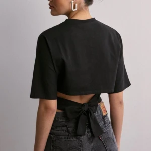 Svart croppad topp med knyt - Supersnygg topp från nelly med knytning i ryggen. Helt slutsåld i alla storlekar på hemsidan. Använd 3 gånger