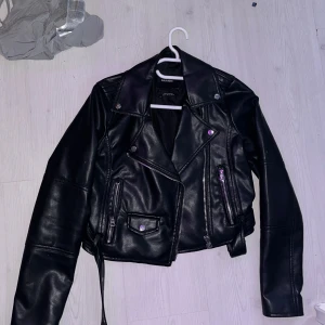 Svart skinnjacka från Pull&Bear - Säljer en snygg svart skinnjacka från Pull&Bear i storlek S. Jackan har en cool bikerstil med dragkedjor och knappar som detaljer. Perfekt för höst och vår, och ger en edgy touch till vilken outfit som helst. Använd ett par gånger men i mycket bra skick!
