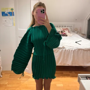 Grön plisserad klänning - Snygg grön plisserad klänning med långa vida ärmar och knytband i midjan. Perfekt för både fest och vardag. Den har en unik struktur som ger en cool look. Passar perfekt nu till julbord och andra juliga festligheter! ❣️🌲🥳
