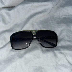 Svarta solglasögon från Louis Vuitton - Snygga svarta solglasögon från Louis Vuitton med en stilren design. De har en rektangulär form och mörka glas som ger ett coolt intryck. Perfekta för både vardag och fest! 🕶️OBS: en del är sönder så ger billigare pris (Äkta vara)!! Söndriga delen finns för att kunna limma på 