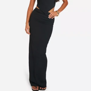 Svart långklänning från Boohoo - Säljer en elegant svart kjolfrån Boohoo. kjolen har en tight passform, perfekt för festliga tillfällen. Materialet är mjukt och stretchigt vilket gör den bekväm att bära hela kvällen. HELT NY!