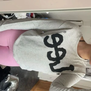 Grå sweatshirt från Lee - Säljer en snygg och bekväm grå sweatshirt från Lee. Den har ett stort svart tryck med Lee-loggan på framsidan. Tröjan är långärmad och perfekt för en avslappnad stil. Passar bra till allt! Det kan finnas defekter men det är inget större som jag ser.