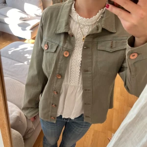 Olivgrön jacka med knappar - Säljer en skitsnygg olivgrön jacka med knappar framtill. Helt ny och är aldrig använd. Perfekt för vår och höst!