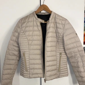 Beige pufferjacka från Rockandblue - Säljer en snygg beige pufferjacka från Rockandblue i storlek 38. Jackan har en stilren design med dragkedja och tryckknappar i guld. Perfekt för höst och vår, och den är i bra skick. vid frågor är det bara att höra av sig!💓