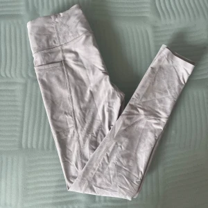 Träningstights - Ljusrosa träningstights med gulddetaljer och fickor från Victorias secret. Storlek S i mycket bra skick endast använda ett fåtal gånger.