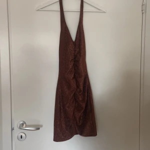 Glittrig brun klänning från H&M Divided - Säljer en superfin glittrig brun klänning från H&M Divided. Den är ärmlös och har en snygg, tight passform som passar perfekt för festliga tillfällen. Materialet är glittrigt och ger en lyxig känsla. Perfekt för en utekväll eller nyårsfest! ✨