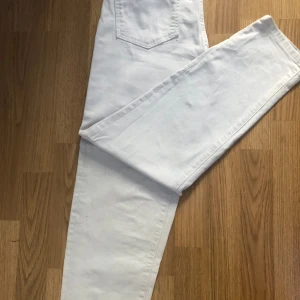 Vita jeansbyxor - Säljer ett par snygga vita jeansbyxor. De har en klassisk design med fem fickor och en knappgylf. Perfekta för en stilren look, oavsett om det är vardag eller fest. Passar bra till både sneakers och klackar!