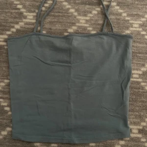 Grå linne från H&M Divided - Säljer ett enkelt och stilrent grått linne från H&M Divided. Perfekt för sommardagar eller som ett basplagg i garderoben. Linnet har smala axelband och är i ett mjukt och bekvämt material.