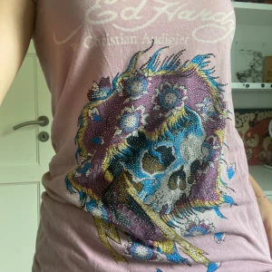 Ed Hardy T-shirt - Säljer denna as snygga vintage ed Hardy tröjan!🙌 Några rhinestones har trillat av och den har ett litet hål men det är inget som synns när man har på sig den💞💞 pris kan diskuteras!!👍