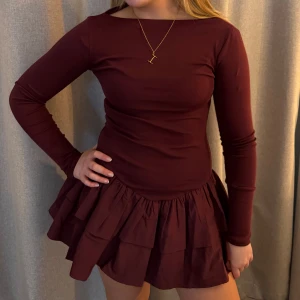 Vinröd klänning med volangkjol - Snygg vinröd klänning från zara(helt ny) med långärmad topp och volangkjol. Perfekt för en stilren look med en touch av elegans. Klänningen har en tight passform upptill och en lekfull volangdetalj på kjolen.