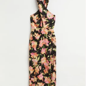 Blommig oanvänd klänning strl M - oanvänd! - Snygg klänning i strl M från H&M med ett färgglatt blommönster i rosa och gröna toner på en svart bakgrund. Klänningen har en unik halterneck-design som ger en elegant touch. Perfekt för sommarens alla tillfällen! 🌸
