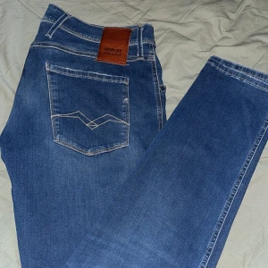 Blå jeans från Replay - Snygga blå jeans från Replay med slitna detaljer och broderade bakfickor. De har en klassisk femficksdesign och en bekväm passform. Perfekta för en avslappnad stil.