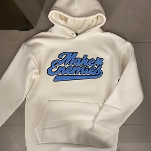 Makes Enemies Vit/beige Hoodie - Säljer en vit hoodie med texten 'Make Enemies' i blått på framsidan. Hoodien har en klassisk design med känguruficka och huva. Perfekt för en avslappnad stil. Har i alla Storlekar- Kom pm och välj din Storlek! Säljer för 399kr fast pris