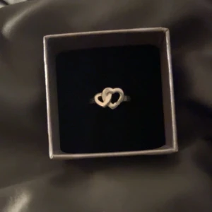 Ring i äkta silver med hjärtan - Elegant ring i rhodinerat äkta silver med två sammanlänkade hjärtan och en liten diamant. Diamanten ligger på 0,015 carat vilket verkar lite men fortfarande äkta 💍 